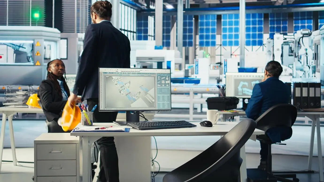 Gerente llegando al trabajo en la oficina de una fábrica fotovoltaica, analizando datos en una PC.